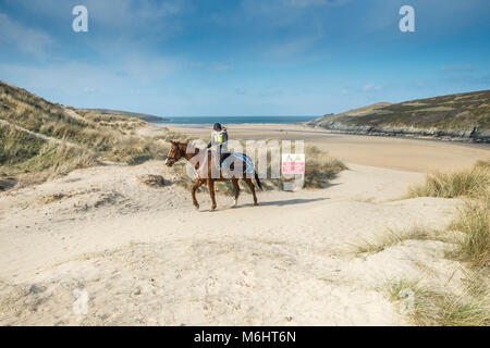 Un cavaliere a cavallo sulle dune di sabbia a Crantock Beach in Newquay Cornwall. Foto Stock