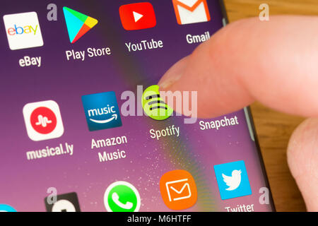 Primo piano dell'app Spotify su uno smartphone selezionato con il dito di una donna che punta verso l'app sul schermo del telefono cellulare Foto Stock