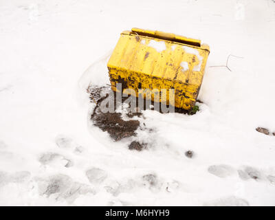 Caduto ribaltato giallo casella di grana sale al di fuori della tempesta di neve; essex; Inghilterra; Regno Unito Foto Stock