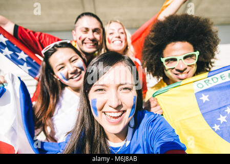 Gruppo misto di tifosi tenendo selfies Foto Stock