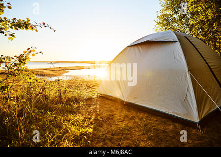 Tenda bianca in piedi in un campeggio sulla spiaggia. Tenda è in piedi sul  lato destro coperto da alberi e piante. Tenda tra palme su un isolano  tropicale Foto stock - Alamy