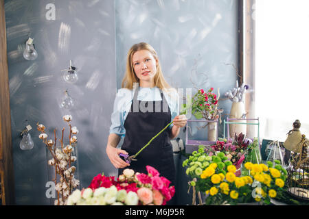 Giovane donna tenendo premuto a lungo fiore e taglio al fioraio Foto Stock