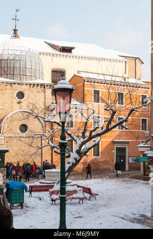 In inverno la neve nel campo dei Santi Apostoli, Cannaregio, Venezia, Veneto, Italia che copre la Santa Chiesa apostoli, panchine e albero con una gita fuori del gruppo Foto Stock