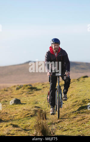 L'uomo cavalca la sua moto lungo una cresta sul Parco Nazionale di Dartmoor, Devon Foto Stock