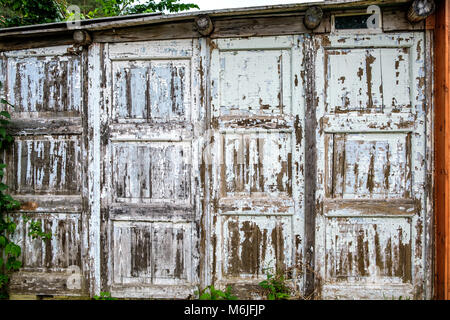Vecchio muro di legno fatto di pannelli di porte scabro in campagna. Vista frontale Foto Stock