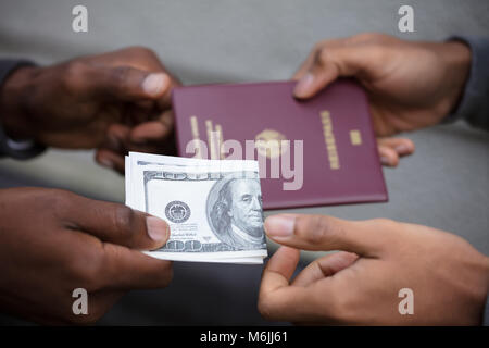 Close-up di due mani lo scambio di passaporto per US Dollar note Foto Stock