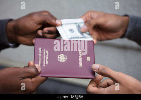 Close-up di due mani lo scambio di passaporto per US Dollar note Foto Stock