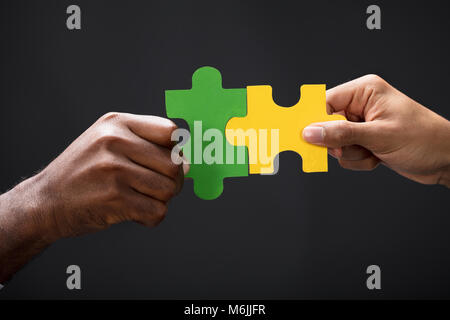 Close-up di Business Partner per la combinazione di due pezzi di un puzzle su sfondo nero Foto Stock