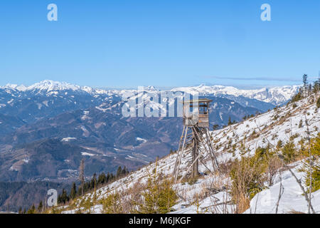 Torre di avvistamento sulla montagna innevata Rennfeld vista sulla vallata Muerztal a montagne Hochturm, Brandstein e Hochschwab Foto Stock
