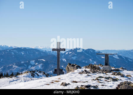 Panoramica paesaggio innevato vista panoramica dalla cima del monte Rennfeld con la croce e la tabella e lontane cime Rosseck e Mugel in inverno Foto Stock