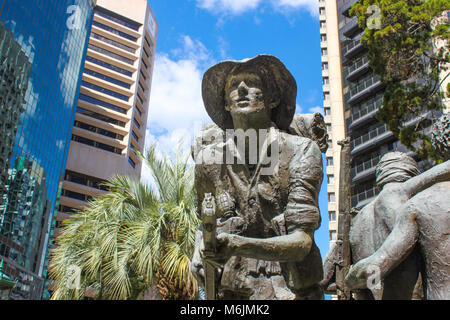 Aussie soldato con pistola e granata si erge tra un moderno ed alto edificio di edifici presso il Memorial di soldati australiani nel CBD di Brisbane Queensland Australia c Foto Stock