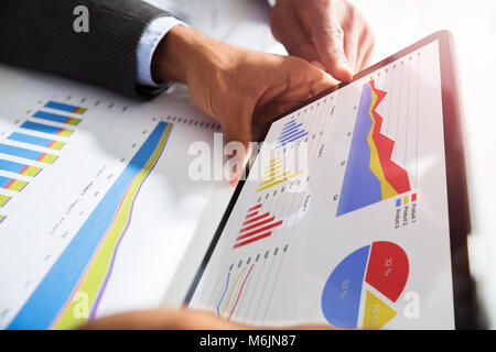 Close-up di due imprenditori che lavorano insieme con grafico finanziario sulla tavoletta digitale Foto Stock