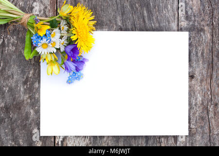 Bouquet di fiori selvaggi sul rovere marrone a tavola con foglio di carta bianco Foto Stock