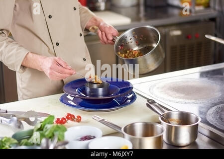 Chef mettendo le mani ratatouille di verdure nella piastra. Foto Stock