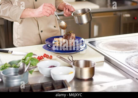 Lo Chef versamento con agnello sause codolo. Foto Stock