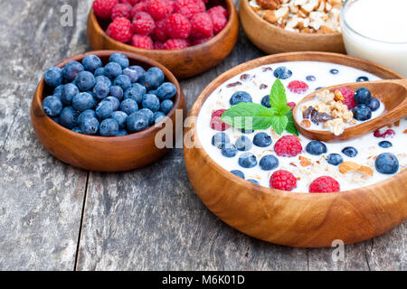 Sana colazione muesli con frutti di bosco e latte nel piatto in legno Foto Stock