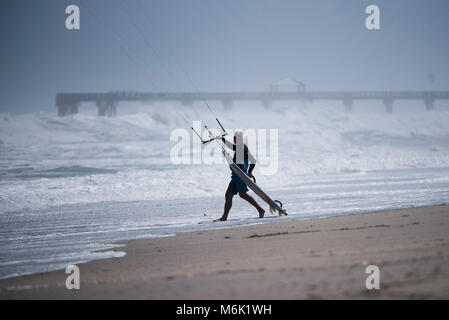 Jupiter, Florida, Stati Uniti d'America. Mar 4, 2018. Un kite surfer corre a lanciare in acqua a nord della spiaggia di Juno Pier in Giove, Fla., domenica 4 marzo 2018. Venti forti da un potente né'pasqua generata ad alta si rigonfia e discontinuo acqua al largo di Palm Beach County. Il servizio meteorologico nazionale con le previsioni che le onde si potrebbe costruire a 15 piedi. Credito: Andres Leiva/Palm Beach post/ZUMA filo/Alamy Live News Foto Stock