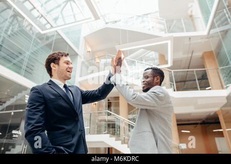 Giovani colleghi dando a ogni altra alta cinque mentre in piedi in un ufficio Foto Stock