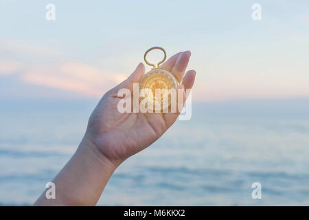 Pocket bussola in mano con lo sfondo del mare. Foto Stock