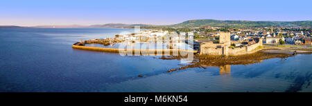 Medievale Castello normanno a Carrickfergus vicino a Belfast in sunrise luce. Antenna ampio panorama con marina, yacht, parcheggio, città di Belfast Lough e lontano Foto Stock