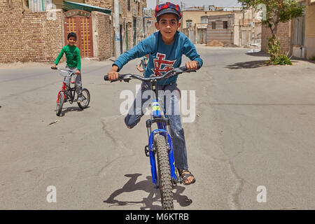 Kashan, Iran - 27 Aprile 2017: Amici di adolescenti in bici nella zona private di bassi edifici nella periferia della città. Foto Stock