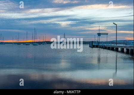 Tramonto al lago Macquarie con Belmont Wharf in primo piano e le barche a vela in background. Il Belmont. AUSTRALIA Foto Stock