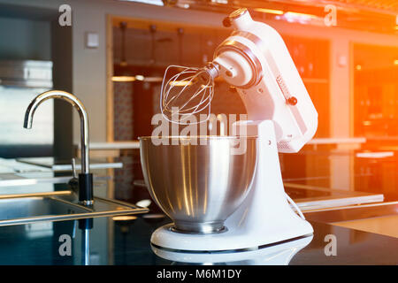 Un bel bianco mixer con un bicchiere di metallo si erge nella cucina moderna Foto Stock