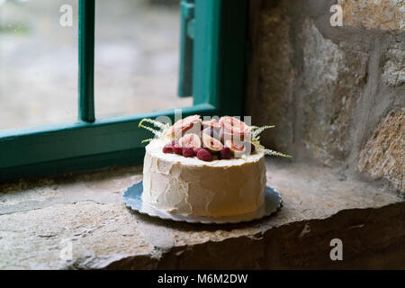 In casa torta nuziale decorata con fiori e frutta Foto Stock