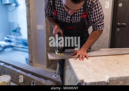 Il contraente il taglio di pavimenti in laminato in senso longitudinale. Lavoratori il taglio di pavimenti in laminato con sega elettrica. Foto Stock