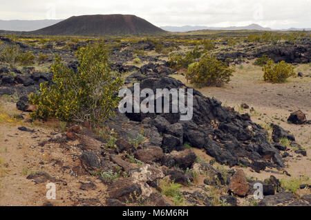 Un antico campo di lava si estende attraverso il Deserto Mojave dal cratere di Amboy vicino alla città di Amboy, CA. Il cratere è un estinto a cono di cenere vulcanica. Foto Stock