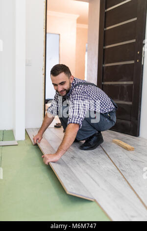 L uomo è la riparazione del pavimento nella casa, pavimenti in laminato in uno stile vecchia boards Foto Stock