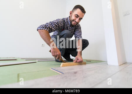 Uomo bello rendere il pavimento laminato l'installazione Foto Stock