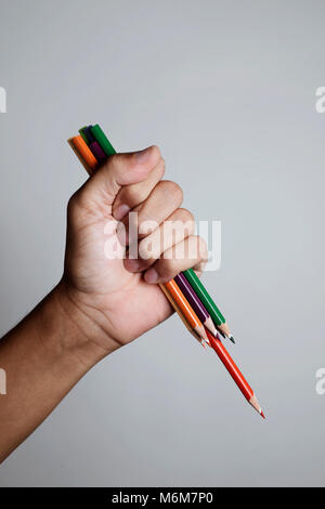 Primo piano di un giovane uomo caucasico con un mazzetto di affilare matite in mano in un gesto minaccioso come brandendo un coltello contro un off-WH Foto Stock