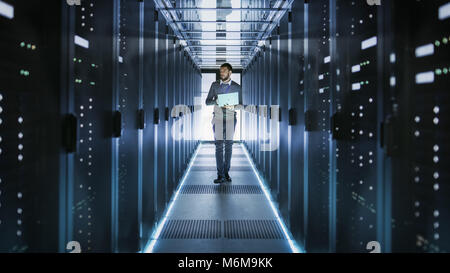 Tecnico IT funziona su computer portatile in grandi data center pieno di server Rack. Egli esegue il programma di diagnostica e manutenzione, Sistema di set up. Foto Stock