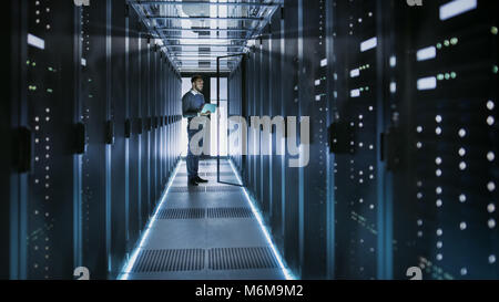Tecnico IT funziona su computer portatile in grandi data center pieno di server Rack. Egli esegue il programma di diagnostica e manutenzione, Sistema di set up. Foto Stock