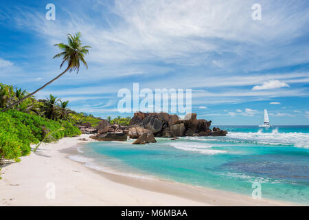 Spiaggia tropicale con palm e una barca a vela in mare, La Digue, Seychelles. Foto Stock