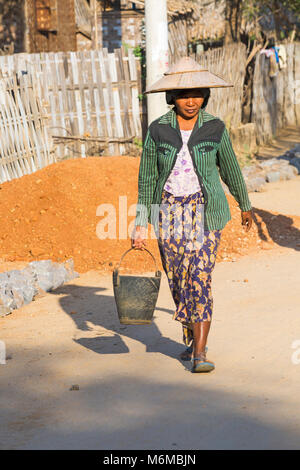 Gli abitanti del villaggio si impegnano strada manuale di lavori di costruzione a West Phwar vide Village, Bagan, Myanmar (Birmania), l'Asia in febbraio - donna che porta la benna Foto Stock