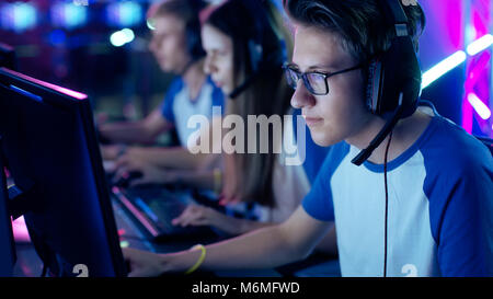 Professional Ragazzo giocatore gioca in video gioco in un torneo di eSports/ Internet Cafe. Indossa occhiali e cuffie con microfono. Foto Stock