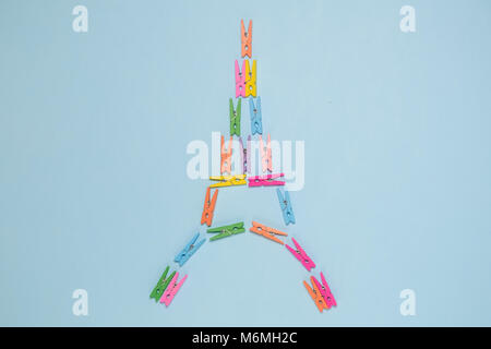 Piatto di laici clothespins colorate a forma di torre eiffel pastello su sfondo blu. La minima nozione Foto Stock