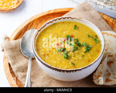 Zuppa di lenticchie con pane pita in una ceramica ciotola bianco su un sfondo di legno. Close up. Foto Stock