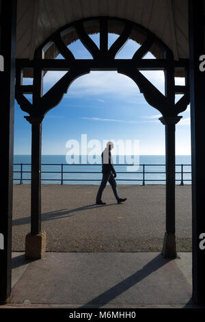 Da solo uomo cammina sul lungomare di Holywell, Eastbourne Foto Stock