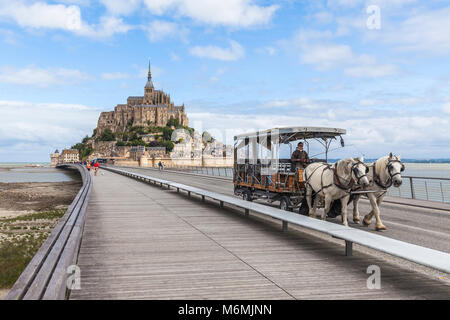 Mont Saint Michel, Francia. Il 14 luglio 2017. Tradizionale carrozza trainata da cavalli che porta i turisti alla isola di Mont Saint Michel Foto Stock