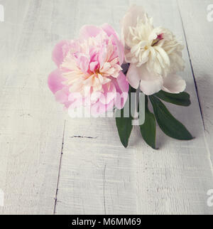 Due le peonie sul vecchio asse di legno. Tonica immagine. Foto Stock