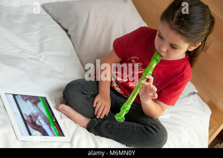 Bambino ad imparare a suonare il flauto con l'aiuto di video online Foto Stock