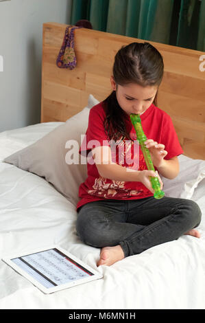 Bambino ad imparare a suonare il flauto con l'aiuto di video online Foto Stock