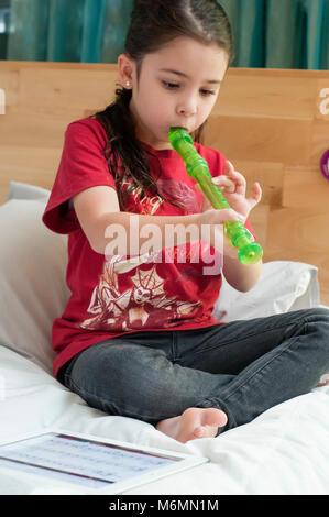 Bambino ad imparare a suonare il flauto con l'aiuto di video online Foto Stock