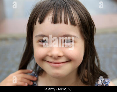 Carino sorridente la sindrome di down girl su sfondo blu Foto Stock