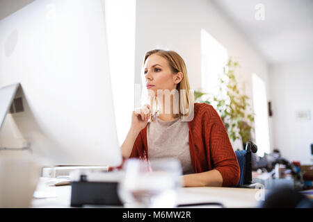 Imprenditrice in sedia a rotelle alla scrivania nel suo ufficio. Foto Stock