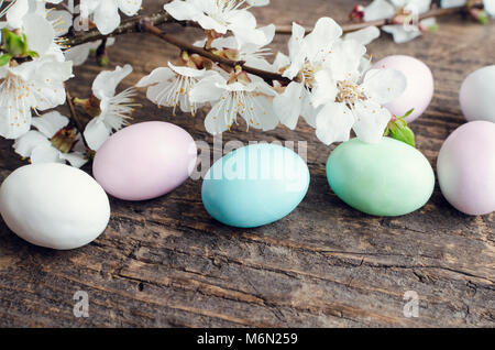 Uova pasquali dipinte in colori pastello con molla di fiori di ciliegio sul vecchio rustico sfondo di legno con posto vuoto per il testo. Felici vacanze di Pasqua. Copia Foto Stock