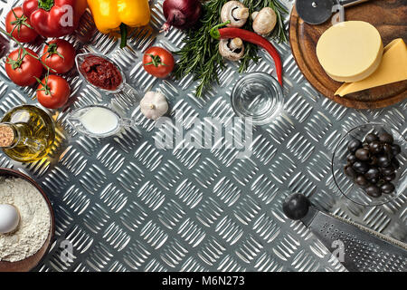 Gli ingredienti alimentari e spezie per la cottura della pizza. Funghi, pomodori, formaggio, cipolla, olio, pepe, sale, l'uovo, grattugia su sfondo di metallo. Copia dello spazio. Vista superiore Foto Stock